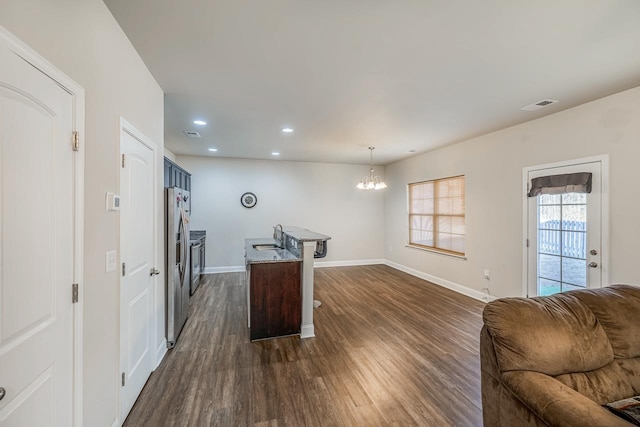 kitchen featuring dark hardwood / wood-style flooring, a kitchen island with sink, decorative light fixtures, a notable chandelier, and stainless steel fridge with ice dispenser