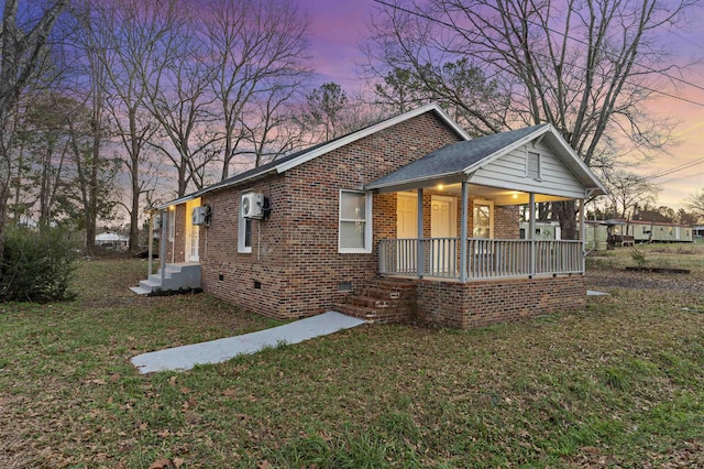 view of front of home with covered porch, a wall unit AC, and a lawn