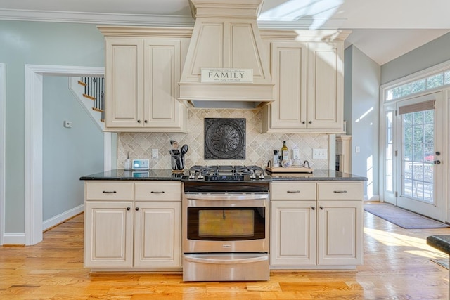 kitchen with premium range hood, backsplash, electric range, and light hardwood / wood-style floors