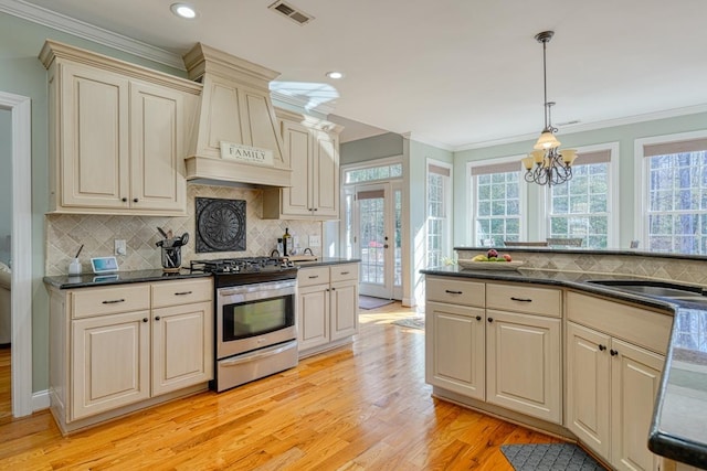 kitchen with pendant lighting, french doors, light hardwood / wood-style flooring, cream cabinetry, and stainless steel range oven