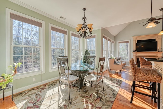 sunroom with ceiling fan with notable chandelier and lofted ceiling