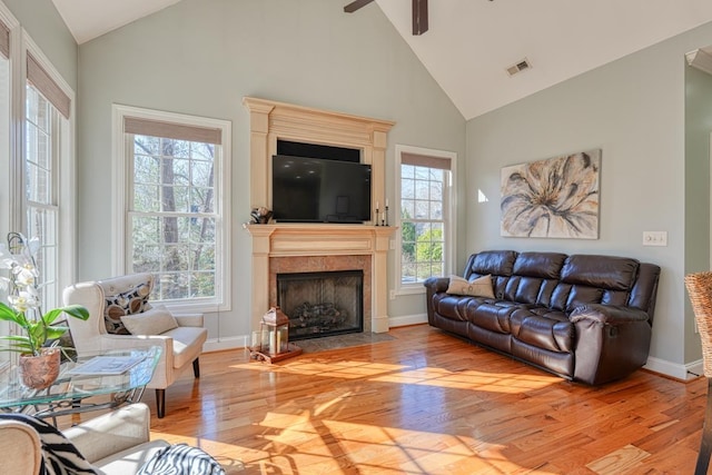 living room featuring a fireplace, light wood-type flooring, plenty of natural light, and ceiling fan