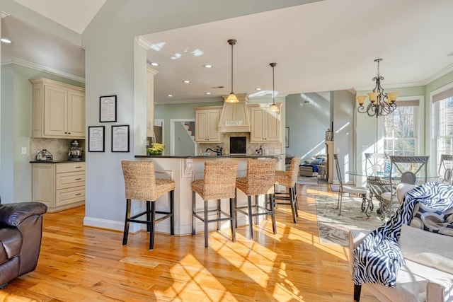 kitchen featuring a notable chandelier, backsplash, cream cabinetry, decorative light fixtures, and kitchen peninsula