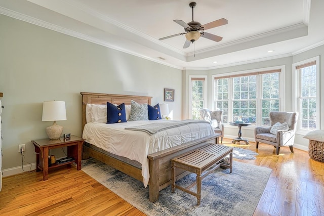 bedroom featuring multiple windows, a tray ceiling, ceiling fan, and crown molding