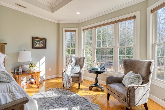 living area with light wood-type flooring, a raised ceiling, and ornamental molding