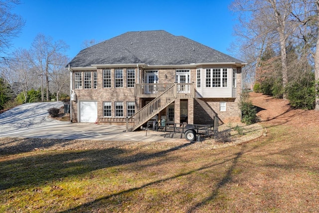 back of property featuring a garage, a yard, a patio, and a wooden deck