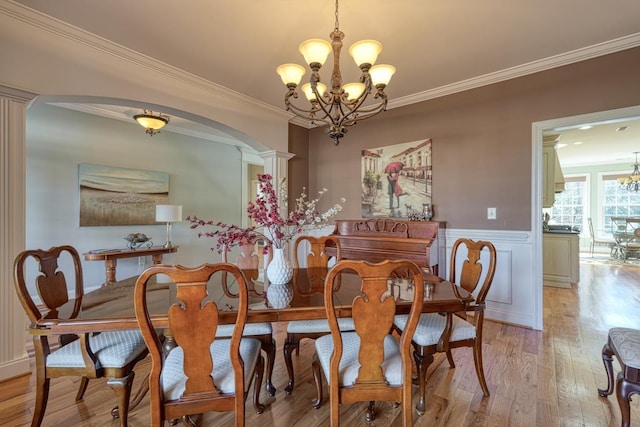 dining space with crown molding, light hardwood / wood-style floors, and an inviting chandelier