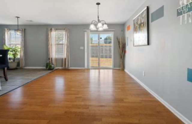 unfurnished dining area featuring plenty of natural light, a chandelier, and hardwood / wood-style flooring