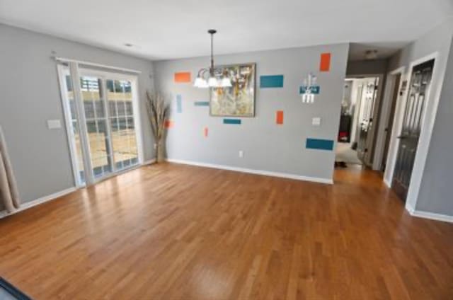 unfurnished dining area with hardwood / wood-style flooring and a chandelier