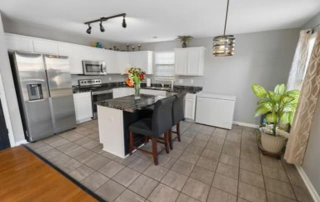 kitchen with a center island, white cabinetry, stainless steel appliances, and a breakfast bar area