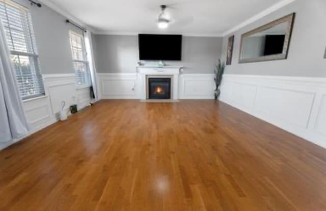 unfurnished living room featuring hardwood / wood-style floors and ornamental molding