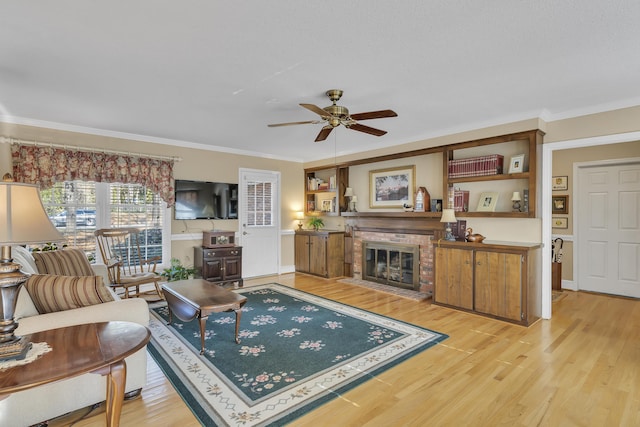 living room featuring a fireplace, ceiling fan, light wood-type flooring, and ornamental molding