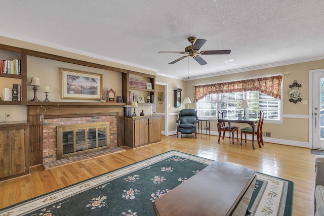 living room featuring ceiling fan, a fireplace, a textured ceiling, and light wood-type flooring