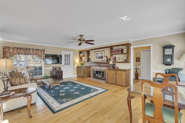 living room featuring ceiling fan, light wood-type flooring, and crown molding