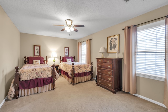 bedroom featuring a textured ceiling, light colored carpet, and ceiling fan