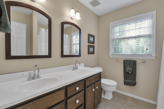 bathroom with tile patterned flooring, vanity, toilet, and a healthy amount of sunlight