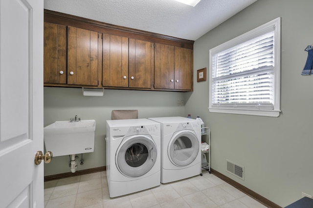 washroom featuring washer and dryer, sink, cabinets, and a textured ceiling