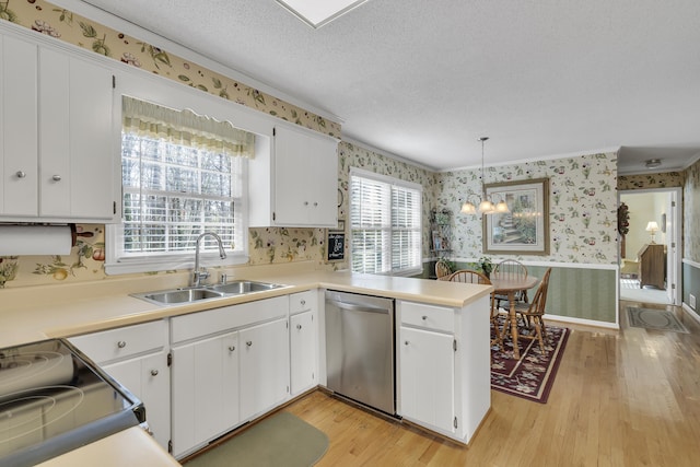 kitchen with kitchen peninsula, stainless steel dishwasher, sink, decorative light fixtures, and white cabinetry