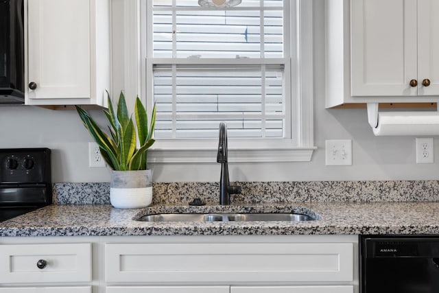 kitchen featuring white cabinets, sink, light stone counters, and black appliances