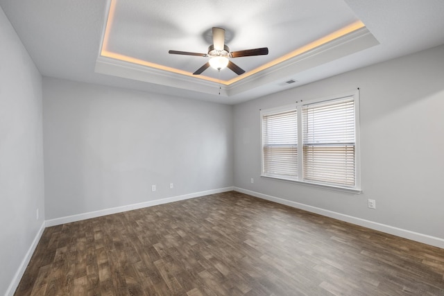 spare room with dark hardwood / wood-style floors, ceiling fan, and a tray ceiling