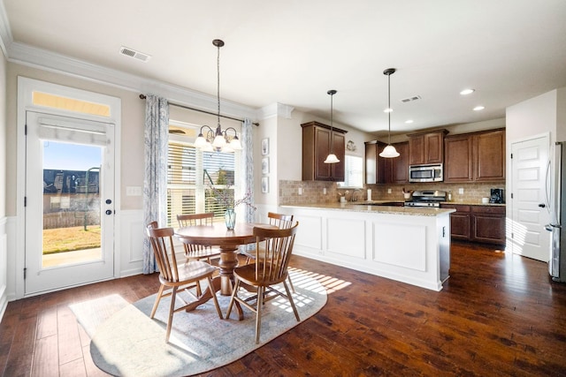 kitchen with appliances with stainless steel finishes, dark hardwood / wood-style floors, pendant lighting, and a notable chandelier