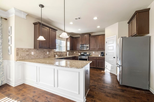 kitchen with kitchen peninsula, appliances with stainless steel finishes, decorative light fixtures, and dark wood-type flooring