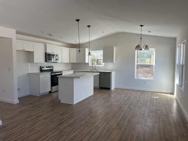 kitchen featuring appliances with stainless steel finishes, pendant lighting, white cabinets, a kitchen island, and lofted ceiling