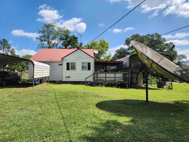 rear view of property with a carport, a yard, and a wooden deck