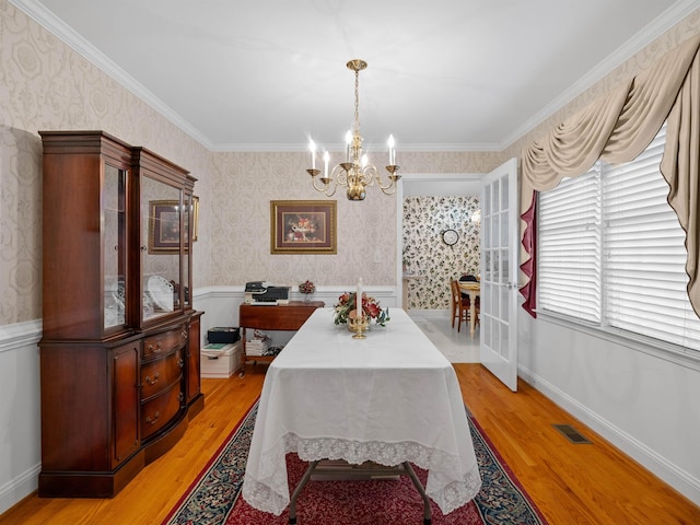 dining area featuring light wood-type flooring, crown molding, and a notable chandelier