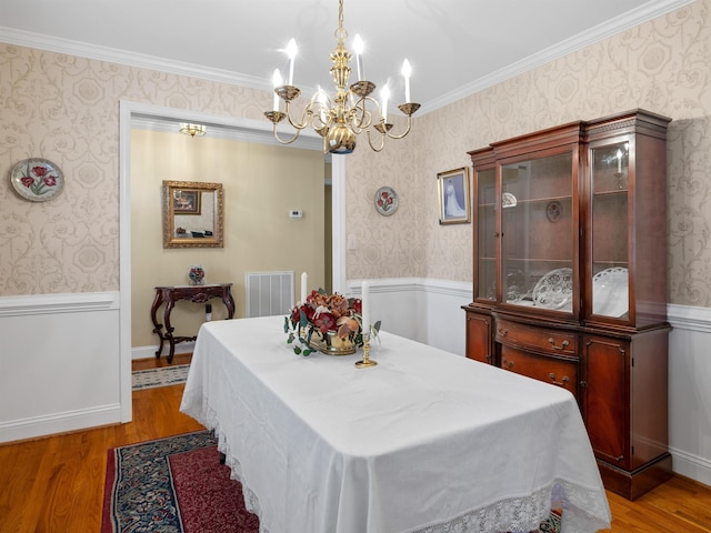 dining space featuring ornamental molding, a notable chandelier, and hardwood / wood-style flooring