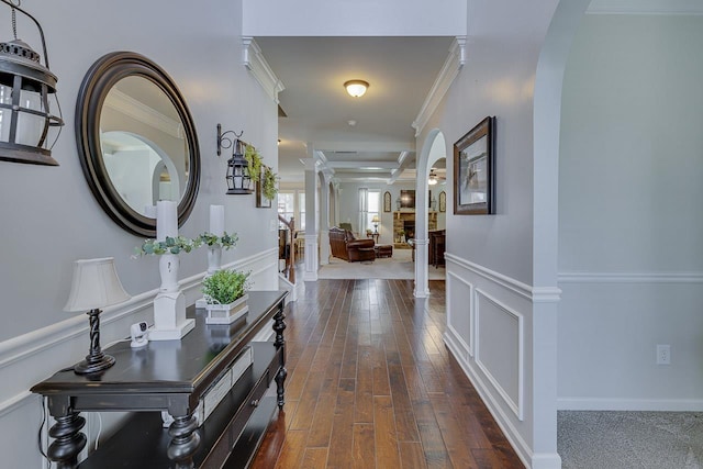 hallway featuring decorative columns, dark wood-type flooring, and ornamental molding