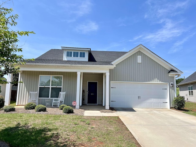 view of front of property with a porch, a garage, and a front lawn