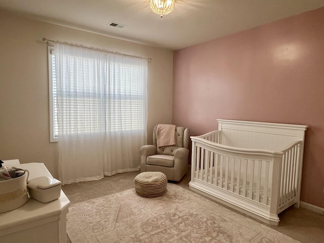 bedroom featuring a crib, baseboards, visible vents, and carpet flooring