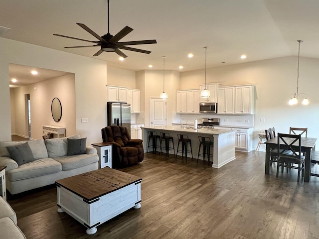 living room with recessed lighting, dark wood finished floors, lofted ceiling, and ceiling fan with notable chandelier