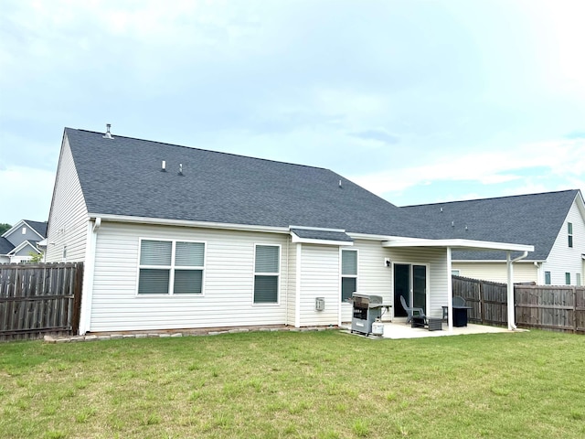 back of house with a patio, a lawn, a fenced backyard, and roof with shingles