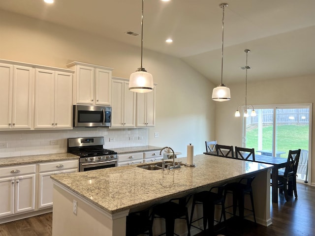 kitchen with decorative backsplash, dark wood-style floors, appliances with stainless steel finishes, vaulted ceiling, and a sink