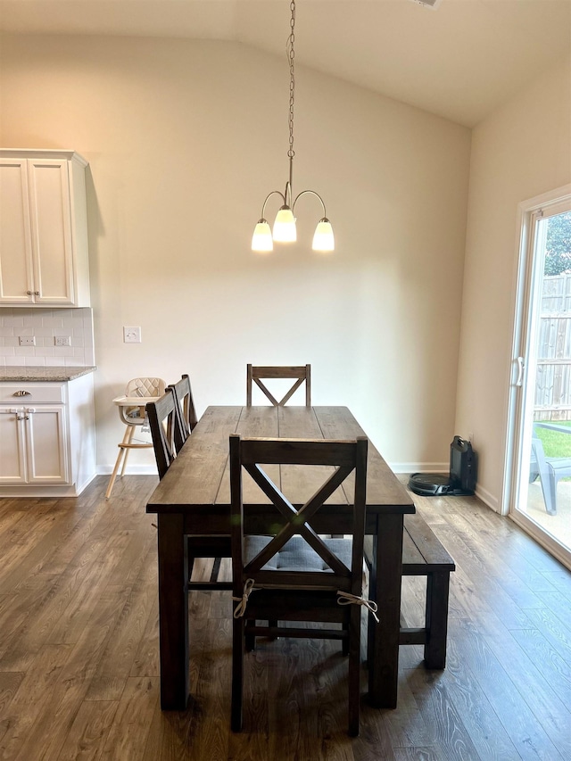 dining area featuring a chandelier, vaulted ceiling, dark wood finished floors, and baseboards