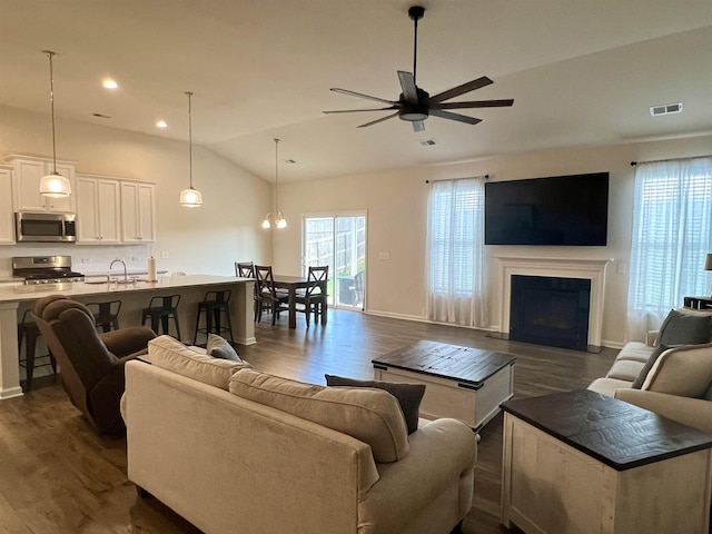 living area with dark wood-style floors, visible vents, and vaulted ceiling