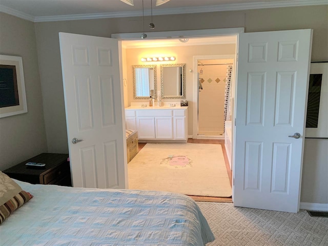 carpeted bedroom with ensuite bathroom and ornamental molding