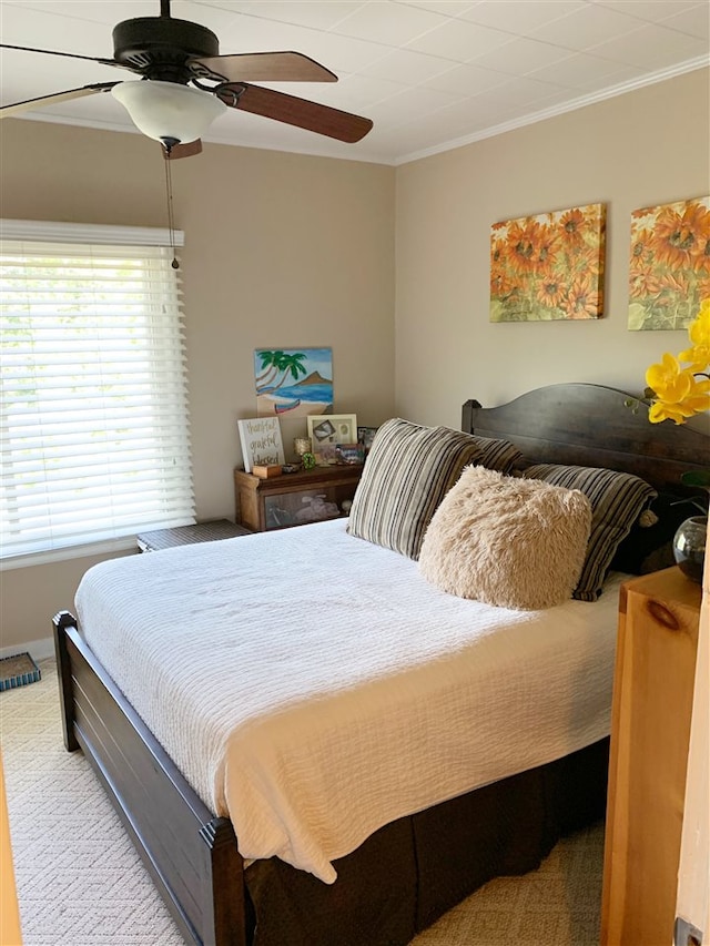 carpeted bedroom featuring ceiling fan and crown molding