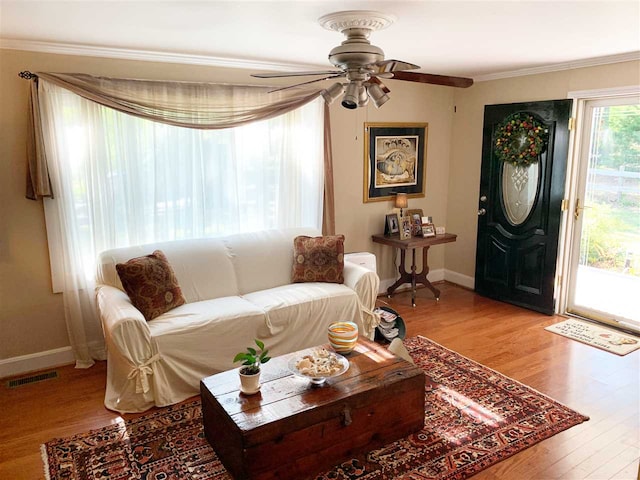 living room with hardwood / wood-style floors, ceiling fan, and crown molding