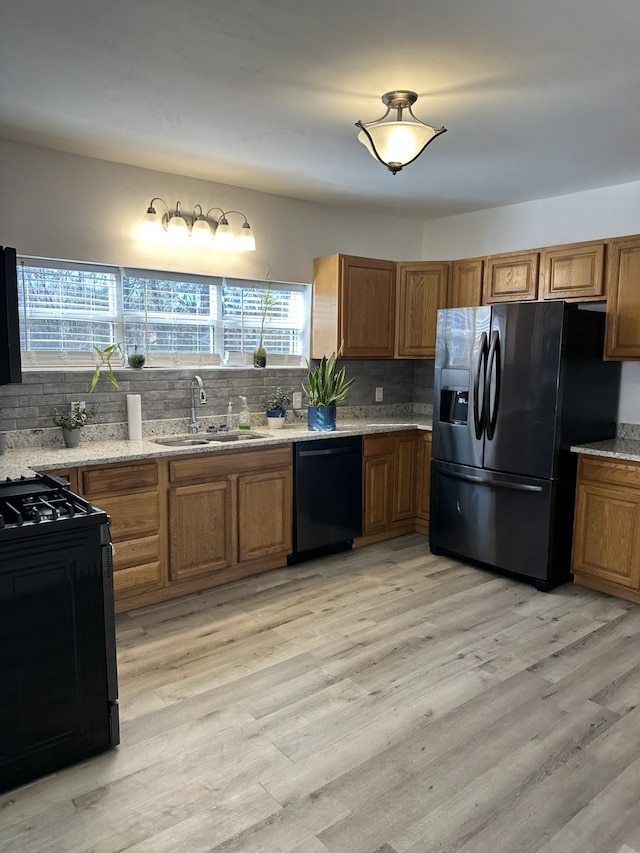 kitchen featuring tasteful backsplash, sink, black appliances, and light wood-type flooring