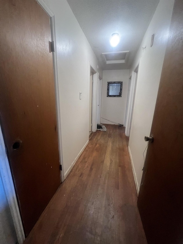 hall featuring attic access, baseboards, and wood finished floors