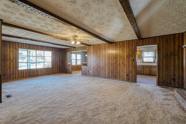 spare room featuring beam ceiling, ceiling fan, carpet, and a textured ceiling