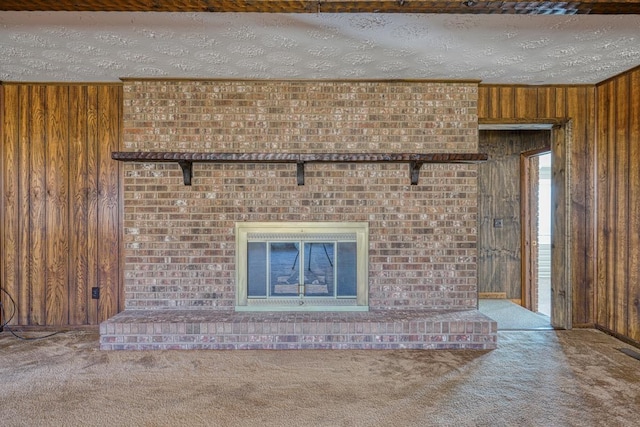 unfurnished living room featuring carpet, a textured ceiling, and wooden walls