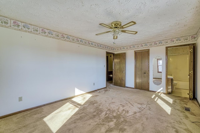 unfurnished bedroom with carpet, ceiling fan, a textured ceiling, and ensuite bath