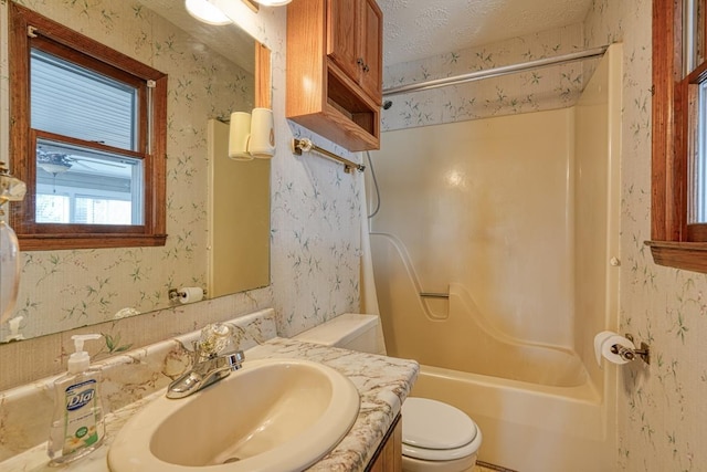 full bathroom featuring a textured ceiling, vanity, toilet, and tub / shower combination