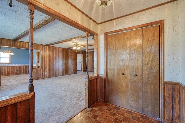 foyer entrance with ceiling fan, dark parquet floors, a textured ceiling, and wooden walls