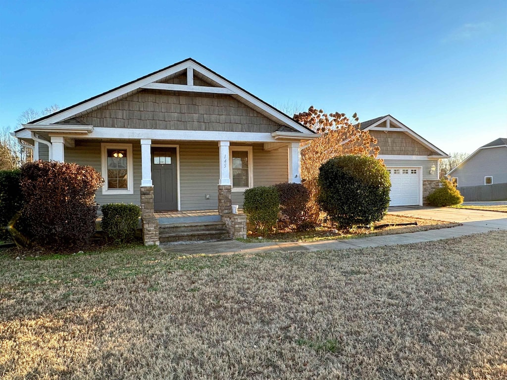 craftsman-style house with a garage, covered porch, and a front yard