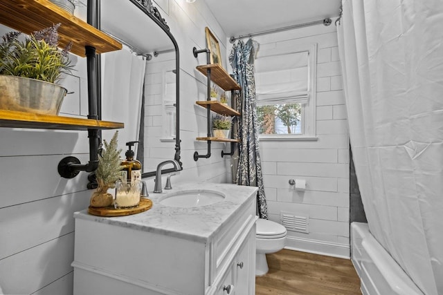 full bathroom featuring vanity, wooden walls, toilet, shower / tub combo with curtain, and wood-type flooring